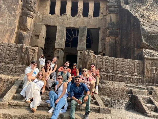 Group of tourists resting on the steps of ancient caves